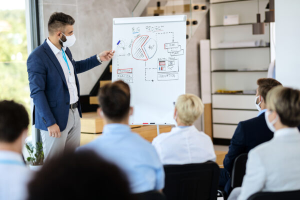 Male entrepreneur with face mask holding business presentation i