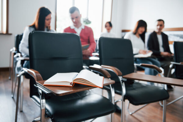Focused on the book. Group of people at business conference in modern classroom at daytime