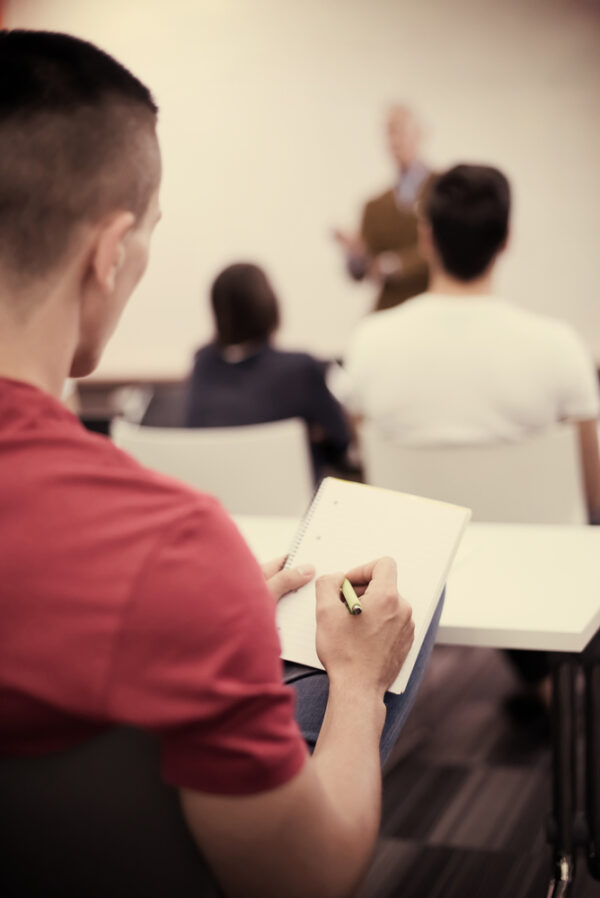 male student taking notes in classroom